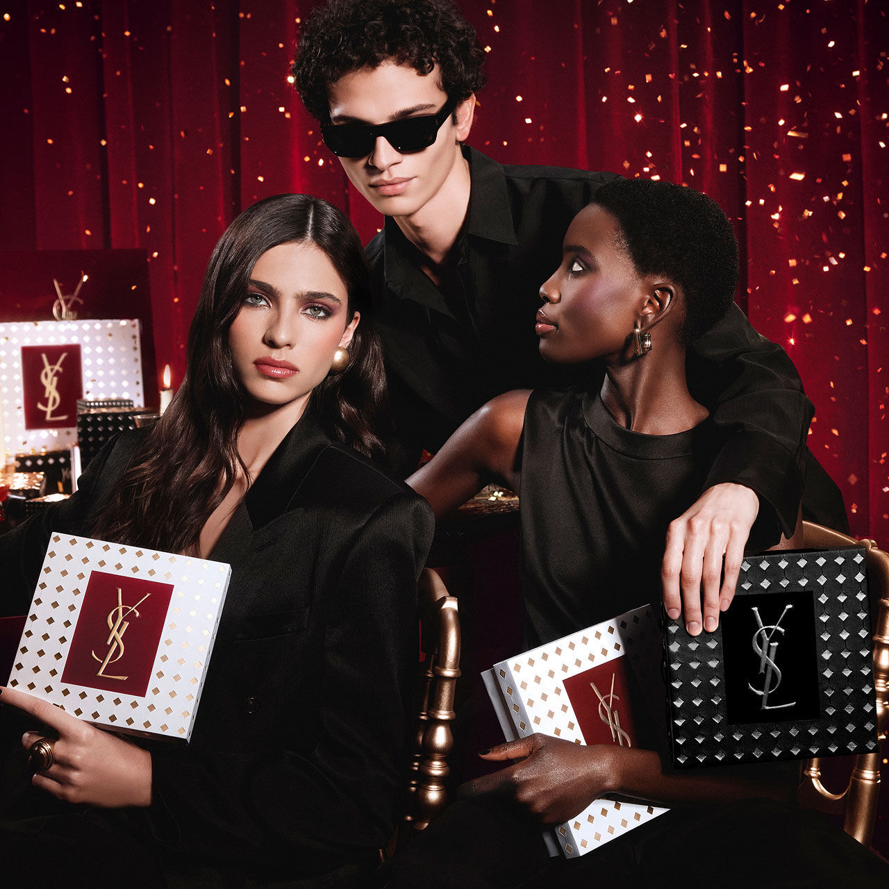 Models posing together holding luxury YSL Holiday gift boxes in a festive atmosphere.