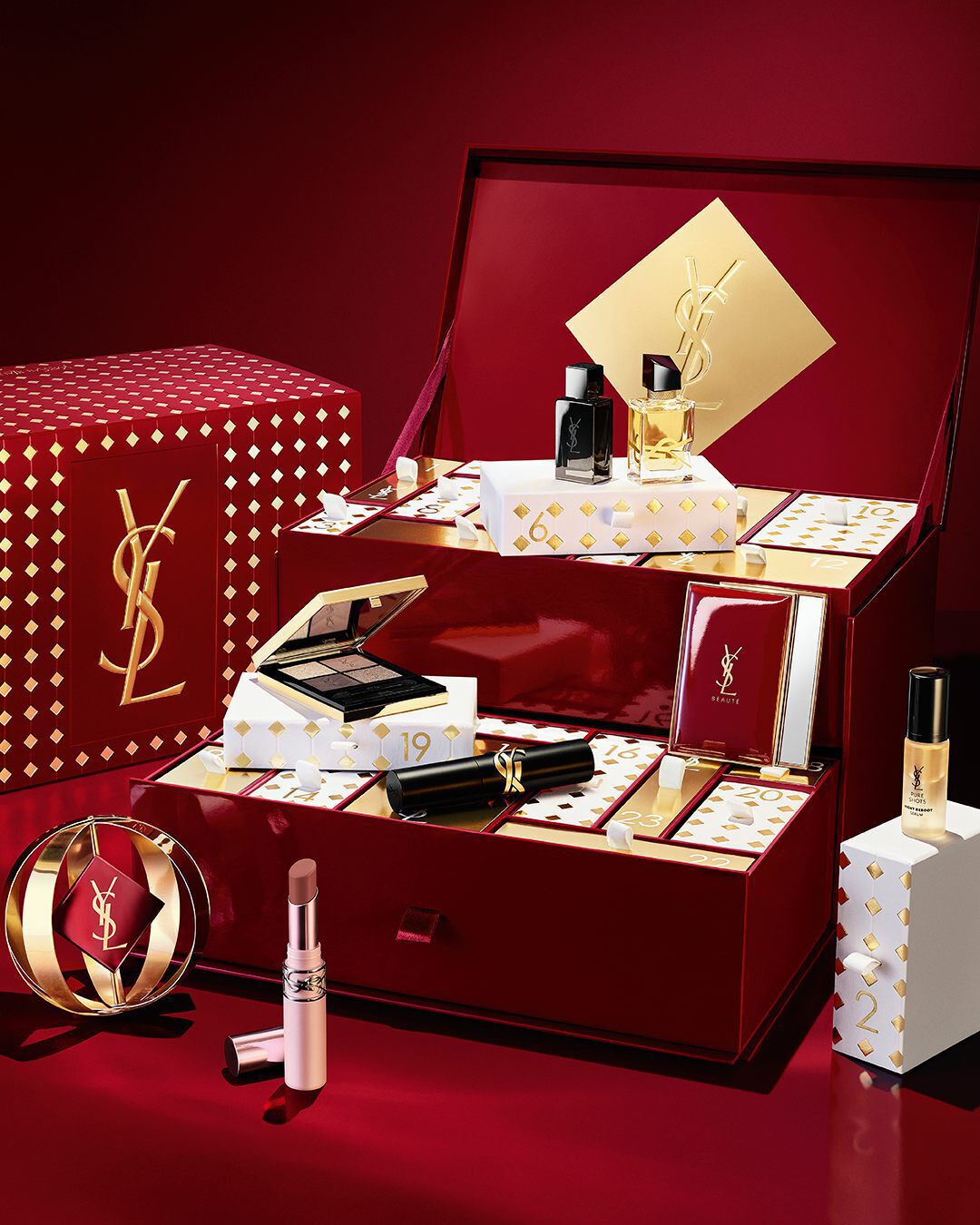 Open burgundy and gold YSL Advent Calendar surrounded by luxury beauty products and gift box.