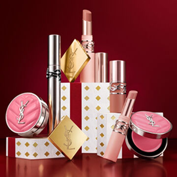 YSL Holiday 2026 makeup collection and fragrance set on gold-dotted white pedestals in burgundy.