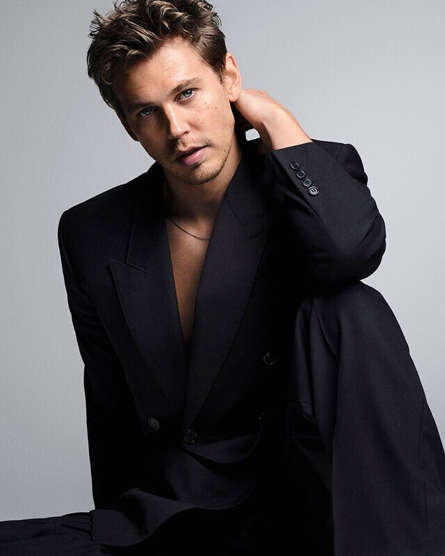 Austin Butler posing in a black suit against a grey background for the MYSLF Eau de Toilette Intense campaign.