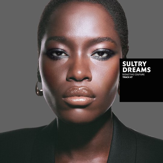 Awar, deep skin tone, with a seductive couture sultry dreams eye look and glossy nude lips, wearing a black blazer.
