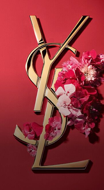Gold YSL Cassandre logo adorned with vibrant pink spring flowers, set against a pink background.