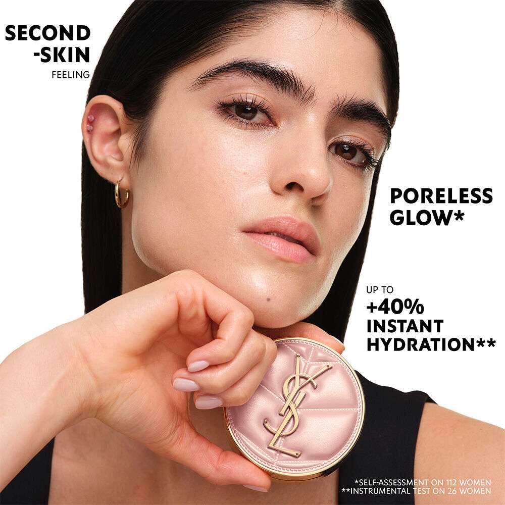 Model holding the YSL SKIN AFFAIR CUSHION FOUNDATION. Text: "Second-Skin Feeling," "Poreless Glow*," "+40% Instant Hydration**". Notes: "*Self-assessment on 112 women, **Instrumental test on 26 women".