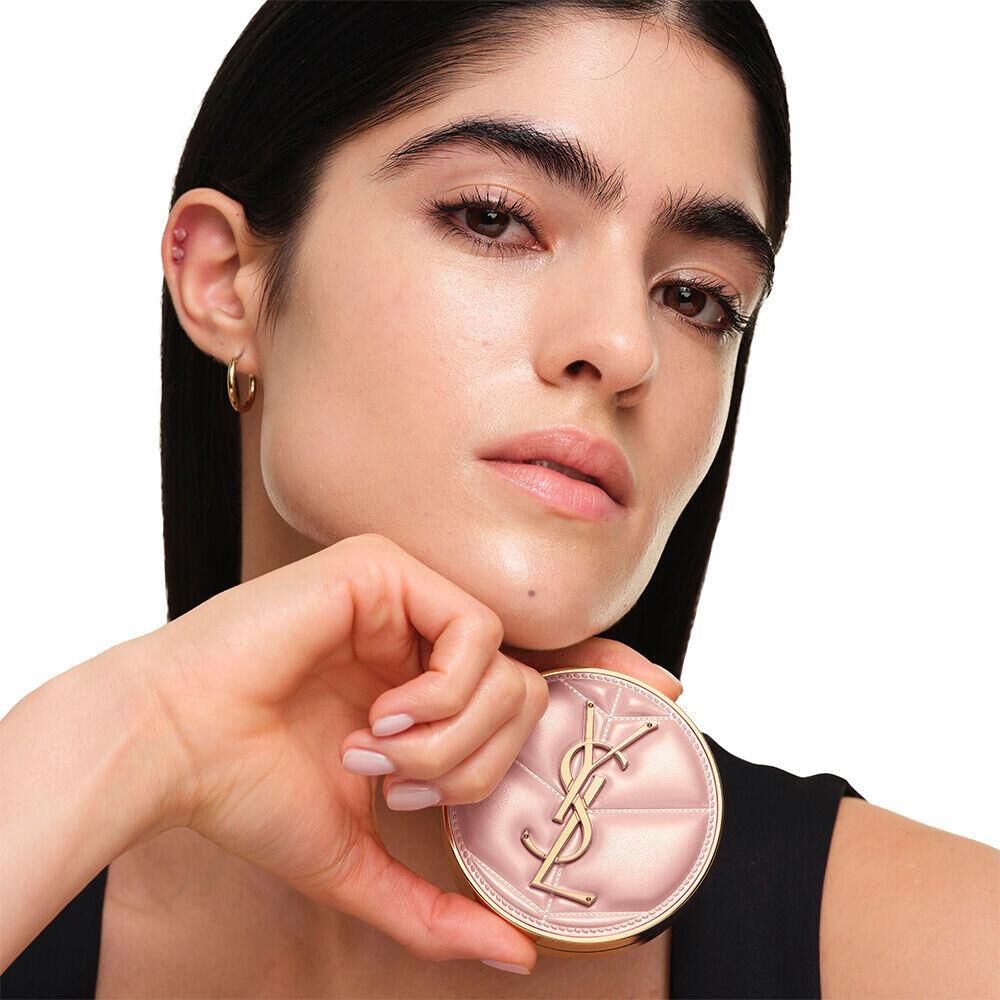 Model with a smooth, radiant complexion holding the pink YSL SKIN AFFAIR CUSHION FOUNDATION to showcase a naturally glowing, flawless skin finish.