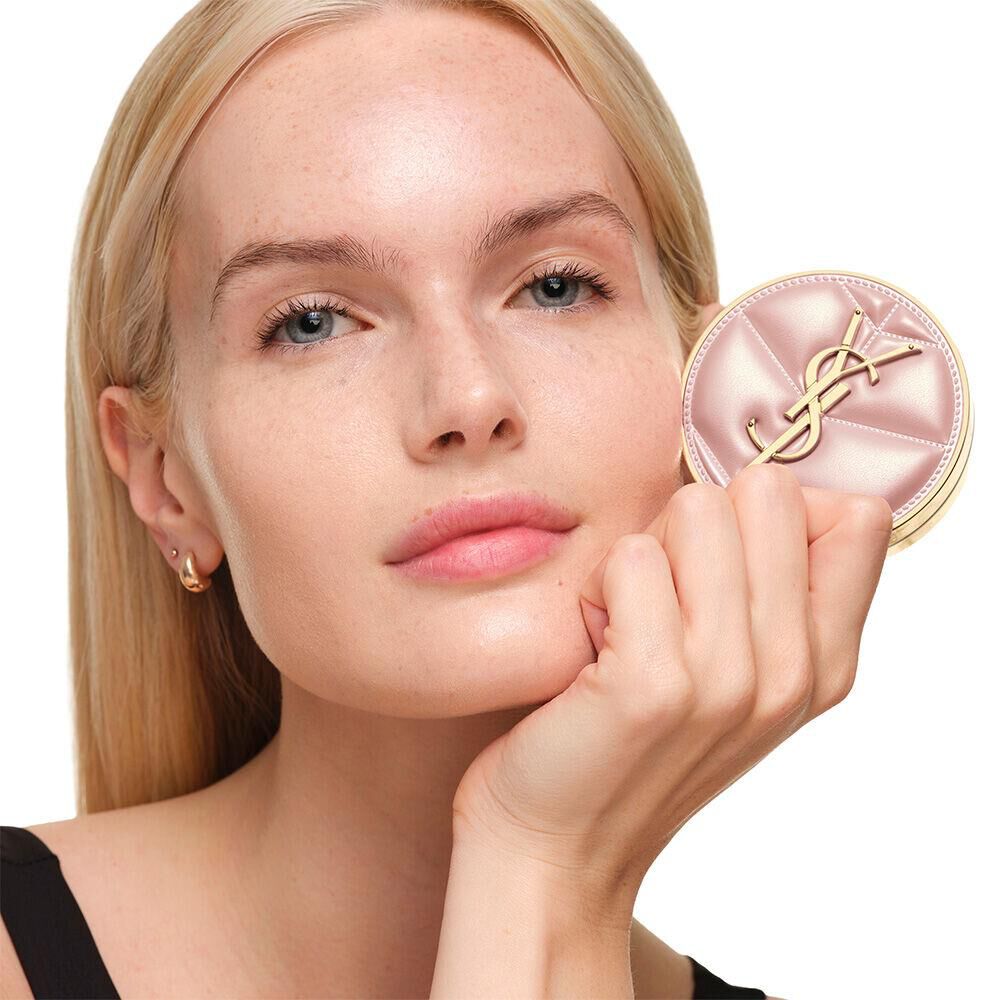Model with a smooth, radiant complexion holding the pink YSL SKIN AFFAIR CUSHION FOUNDATION to showcase a naturally glowing, flawless skin finish.