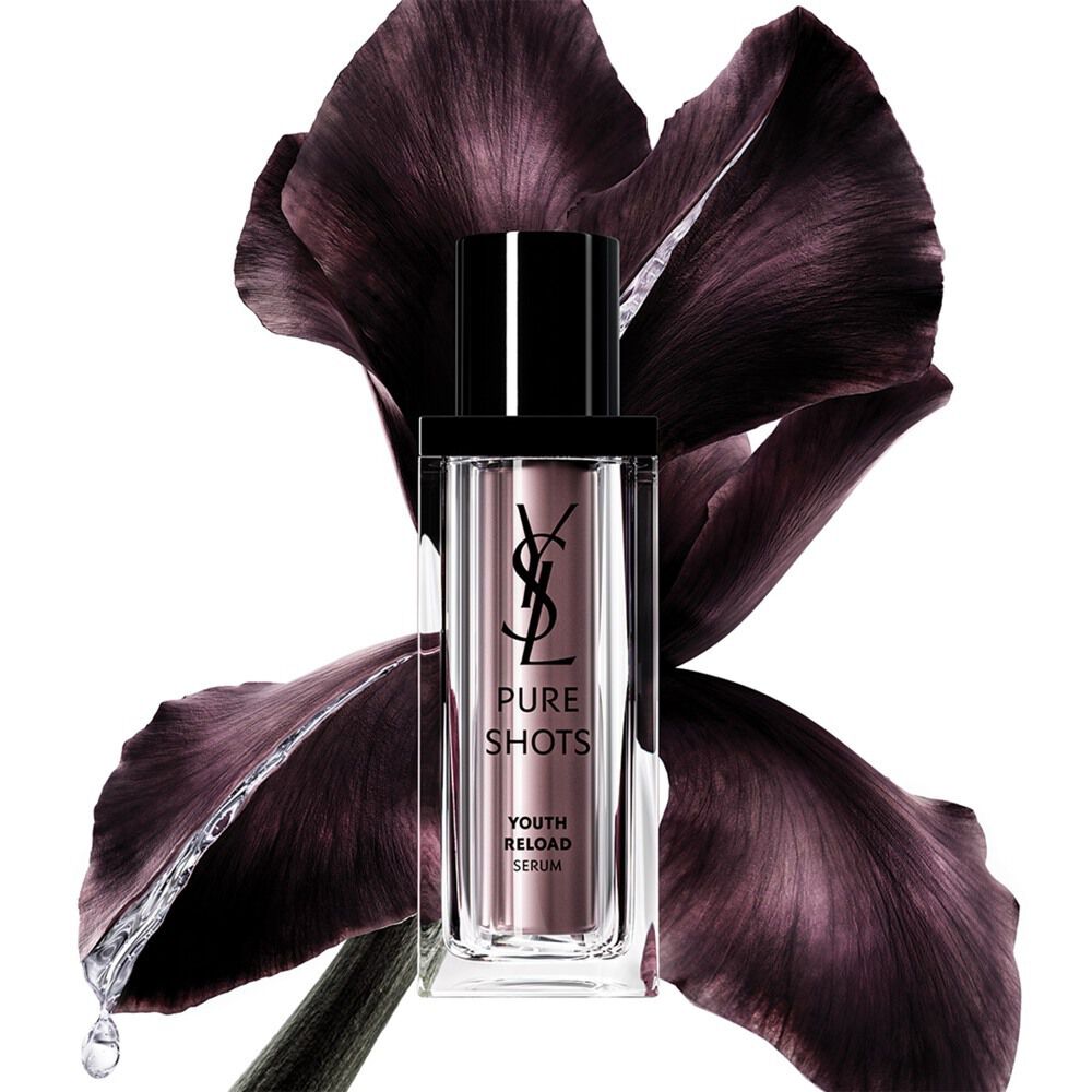 YSL Beauty Pure Shots Youth Reload Serum bottle, elegantly positioned in front of a dark purple iris flower.