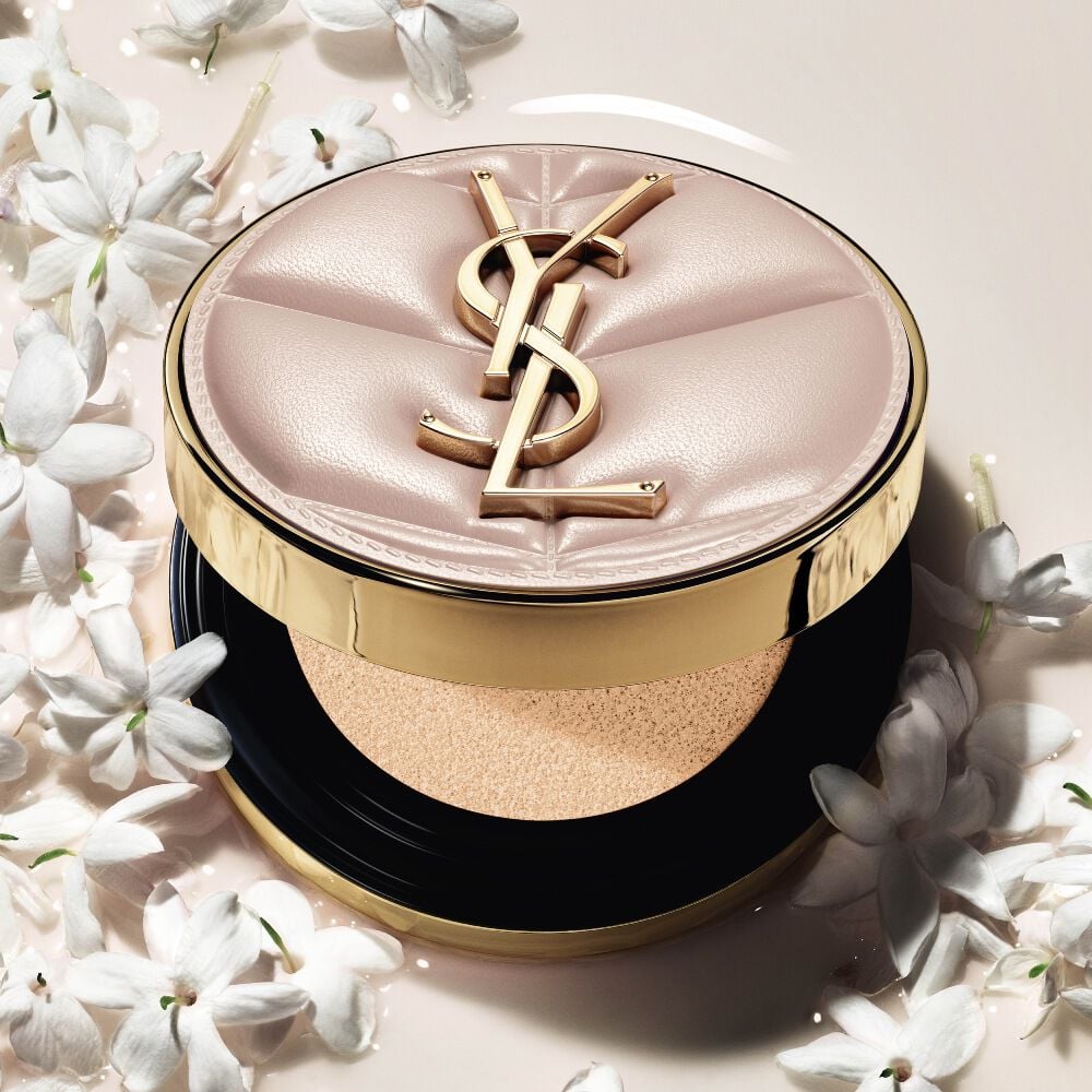 Close-up of YSL SKIN AFFAIR SOFT GLOW CUSHION in a pool of liquid foundation and jasmine flowers. Radiant, sensorial finish.