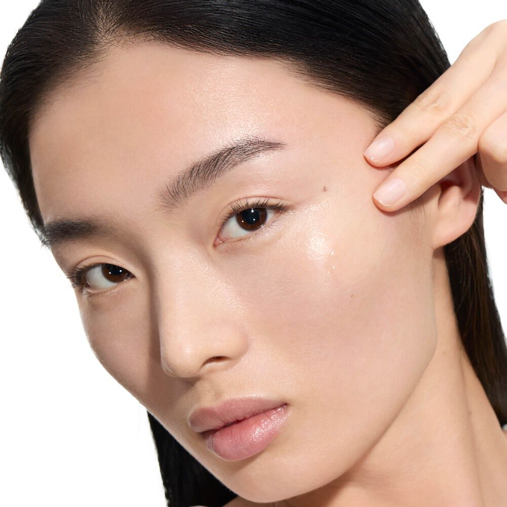 Wen, YSL Beauty model, with fair skin, applying a drop of Pure Shots Youth Reload Serum to her cheek.